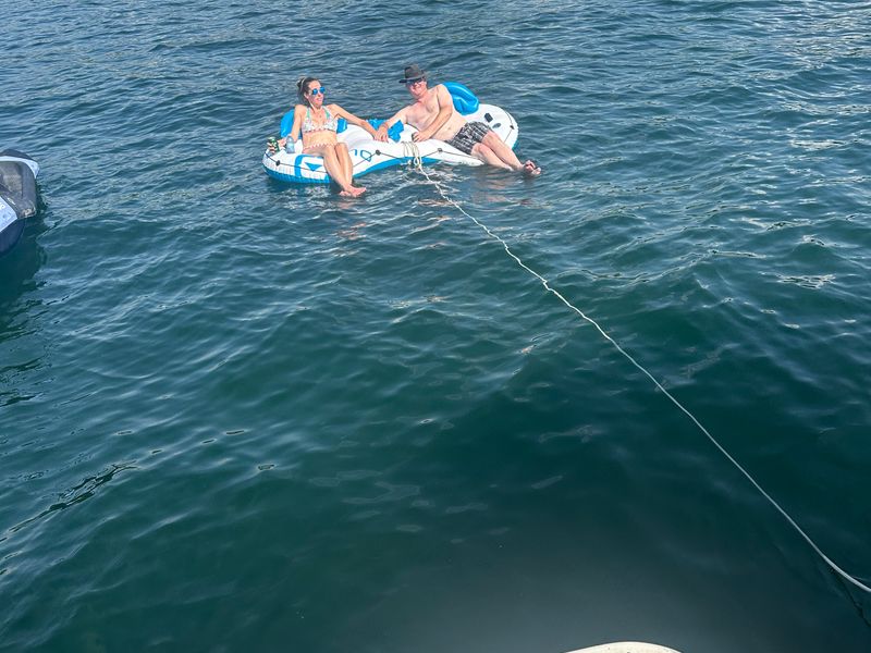 Friends floating on the water tied to the boat